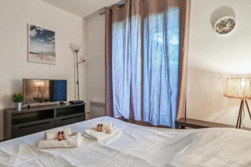 um quarto com uma grande cama branca com toalhas em Joli T2 - domaine de la Coudouliere - Piscine em Six-Fours-les-Plages