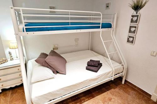 ein Etagenbett mit einem weißen Etagenbett mit Kissen in der Unterkunft El Principe. Widok na morze. Garaż. Plaża 10 m in Santa Pola