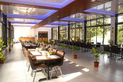 Ashoka Lawns and Resort في آليباغ: غرفة طعام مع طاولات وكراسي ونوافذ