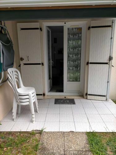 a white chair sitting on the front porch of a house at Petit nid douillet rose et bleu in Ozillac