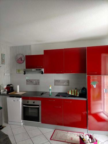 a kitchen with red cabinets and a stove top oven at Petit nid douillet rose et bleu in Ozillac