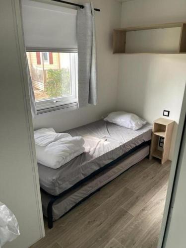 une petite chambre avec un lit et une fenêtre dans l'établissement Mobil-home L50, à Narbonne