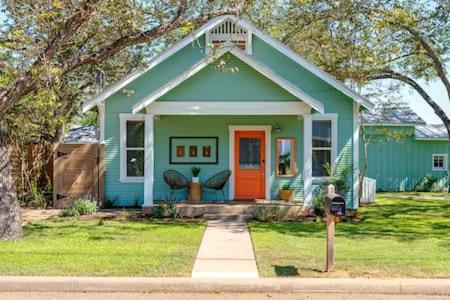 フレデリックスバーグにあるHello Bungalow - Hot Tub Fire Pit 1 BLK to Mainの庭にあるオレンジ色のドアが付いた緑の家