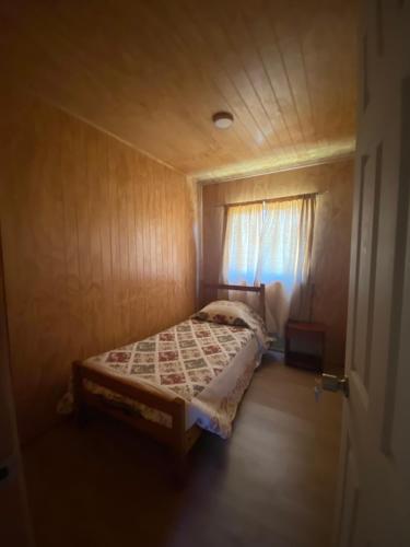 a small bedroom with a bed with a window at Cabañas Mili in Panguipulli