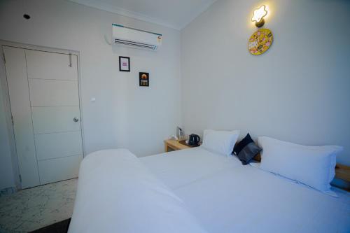 a bedroom with two white beds and a clock on the wall at Stay Inn Kaashvi (A unit of Admire India Tourism Pvt. Ltd.) in Varanasi