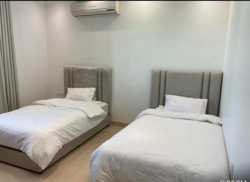 two beds in a room with white sheets at Alwaha-Appartement in Riyadh