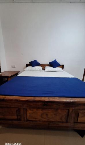 a large wooden bed with blue sheets and pillows at Dark waves villa in Nilaveli