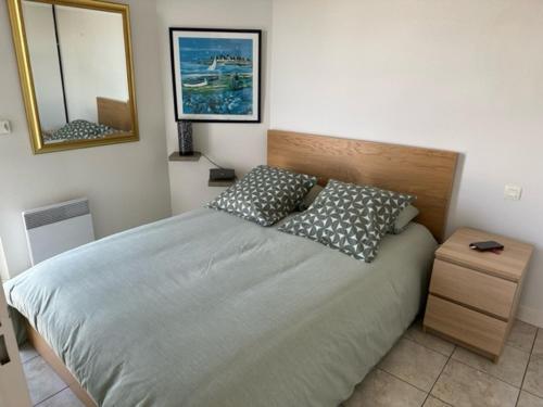 une chambre avec un lit avec deux oreillers et un miroir dans l'établissement Ref 121 - Bel appartement moderne avec vue mer et port Crouesty pour quatre personnes, à Arzon