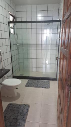 ein Badezimmer mit einer Dusche, einem WC und einer Glastür in der Unterkunft Apartamento grande Vitória in Vitória