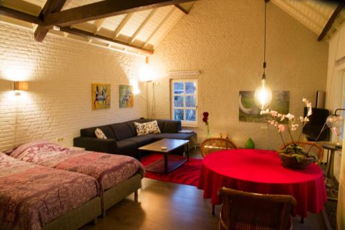 Sala de estar con cama y mesa roja en Op de Smelen 1 - 43 m2, en Blitterswijck