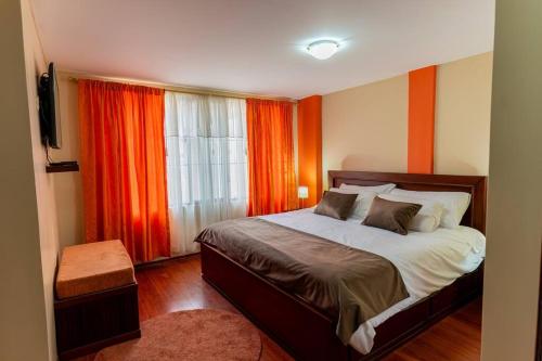 Schlafzimmer mit einem Bett und einem Fenster mit orangefarbenen Vorhängen in der Unterkunft Casita Linda Baños in Baños