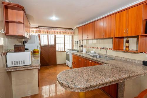 a kitchen with wooden cabinets and a granite counter top at Casita Linda Baños in Baños