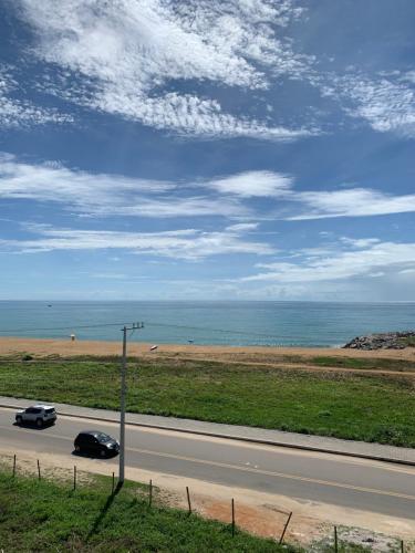 two cars driving down a road next to the ocean at Bela vista a beira mar in Marataizes