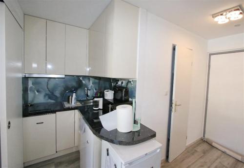a kitchen with white cabinets and a black counter top at Sol-y-Days Cyprianes appartement moderne avec piscine in La Grande-Motte