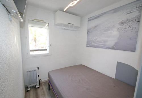 a small bedroom with a bed and a window at Sol-y-Days Cyprianes appartement moderne avec piscine in La Grande-Motte