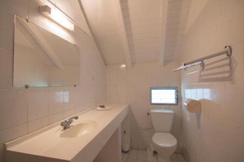 a white bathroom with a sink and a toilet at Chambres d'hôte Beauséjour in Beauséjour