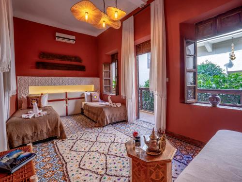 a bedroom with two beds in a room with red walls at Riad Maialou & SPA in Marrakech