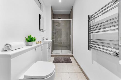 uma casa de banho branca com um chuveiro e um WC. em Modern One Bedroom Flat - Near Heathrow, Windsor Castle, Thorpe Park - Staines London TW18 em Londres