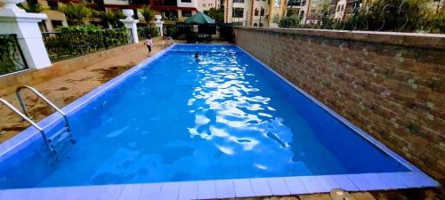 a large blue swimming pool with a person in the water at the perfect affordable apartments in Nairobi
