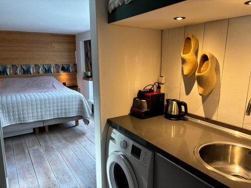 a room with a bed and a kitchen with a washing machine at Luxury studio on Robs houseboat special for couples in Amsterdam