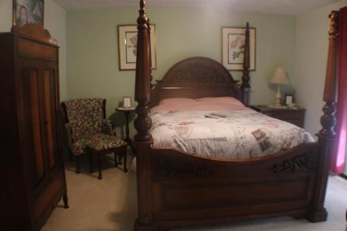 1 dormitorio con cama con dosel y silla en Serenity Hill Bed and Breakfast en Sloans Crossing
