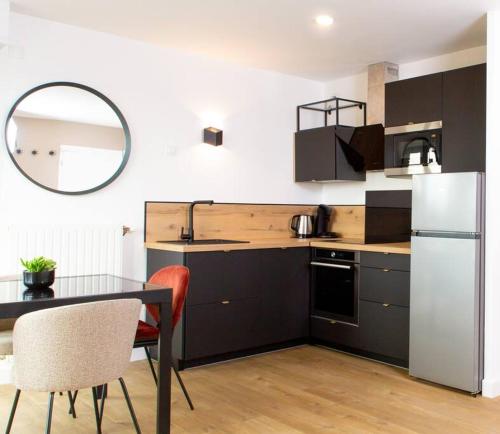 une cuisine avec une table et un réfrigérateur blanc dans l'établissement Perle d'Évasion - Cinéma privée - 15 minutes Paris, à Athis-Mons