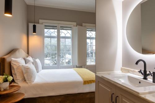 sypialnia z łóżkiem, umywalką i oknem w obiekcie Aparthotel Largo da Oliveira w mieście Guimarães