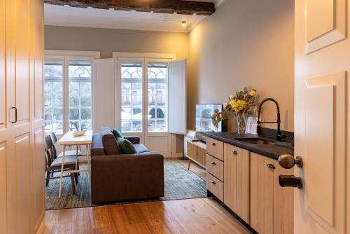 a kitchen and living room with a couch and a sink at Aparthotel Largo da Oliveira in Guimarães