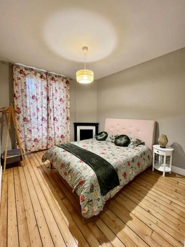 - une chambre avec un grand lit et du parquet dans l'établissement Maison Meulière avec jardin, à Épernay