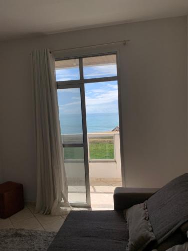 a bedroom with a large glass door with a view of the ocean at Bela vista a beira mar in Marataizes