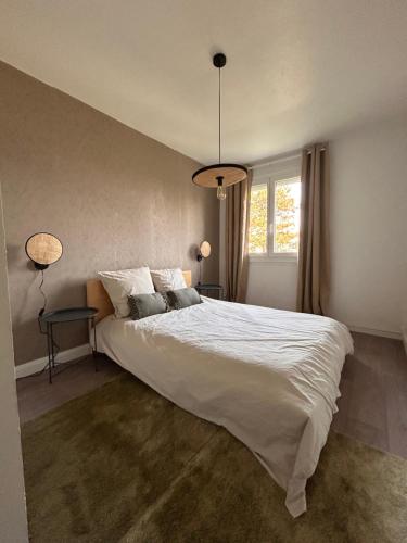 ein Schlafzimmer mit einem großen weißen Bett und einem Fenster in der Unterkunft LA BELLE ESCALE in Belfort