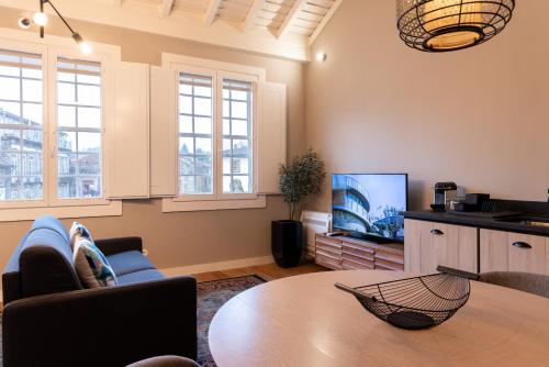 a living room with a table and a tv at Aparthotel Largo da Oliveira in Guimarães