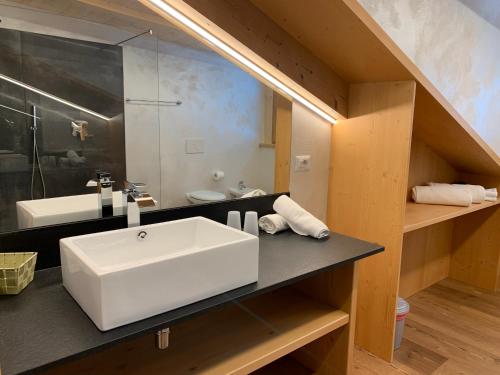 a bathroom with a white sink and a mirror at Attico Penia Chalet Orchidea in Penia