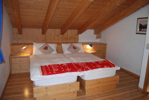 a bedroom with a bed with a red blanket on it at Attico Penia Chalet Orchidea in Penia