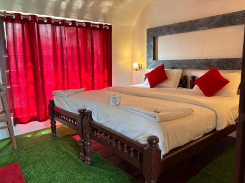 a bedroom with a large bed with red curtains at PUNNAMADAKKARAN CRUISE in Alleppey