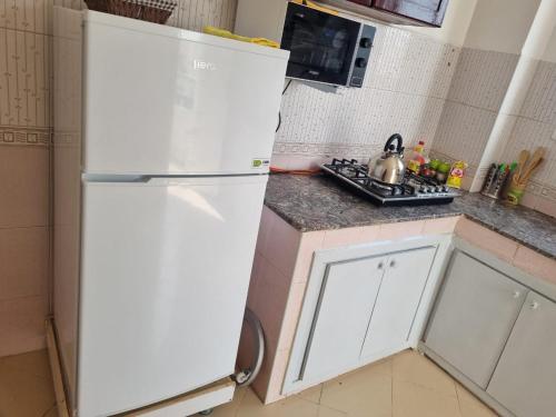 a white refrigerator in a kitchen with a stove at Appartement propre et soigné in Sale