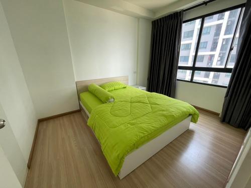 - une chambre avec un lit doté d'une couette verte et d'une fenêtre dans l'établissement 2BR Apartment, à Bangkok