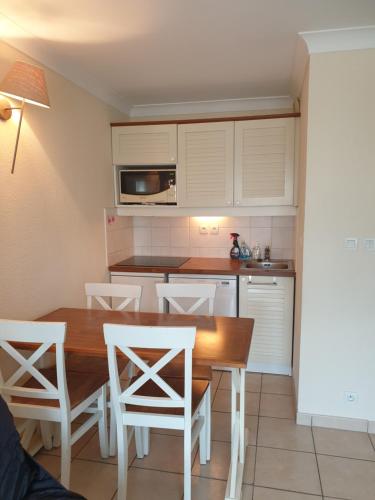 - une cuisine avec une table en bois et des chaises blanches dans l'établissement Lacanau ocean piscine et océan, à Lacanau-Océan