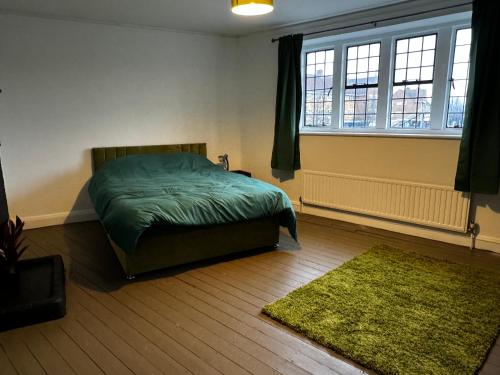 a bedroom with a green bed and a green rug at The Airman in Feltham