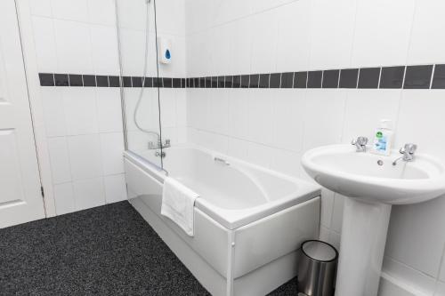 a white bathroom with a sink and a bath tub and a sink at Cosy two bedroom property! in Featherstone