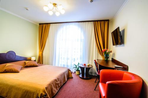 1 dormitorio con cama, escritorio y ventana en Terminal-A Hotel, en Leópolis