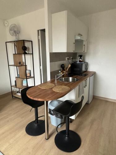 - une cuisine avec une table en bois et deux tabourets de bar dans l'établissement L'escale, Studio proche Gare Melun avec parking privé, à Dammarie-les-Lys