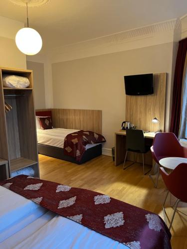 a hotel room with a bed and a desk and a table at Hotel Skandia in Helsingør