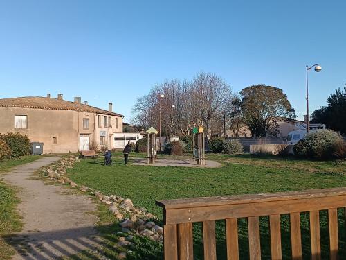 a wooden fence next to a yard with a house at Jolie maison de village in Capendu