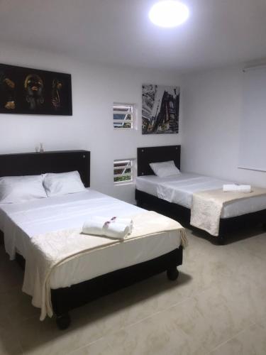 2 camas en una habitación con paredes blancas en San Alejo en Tuluá