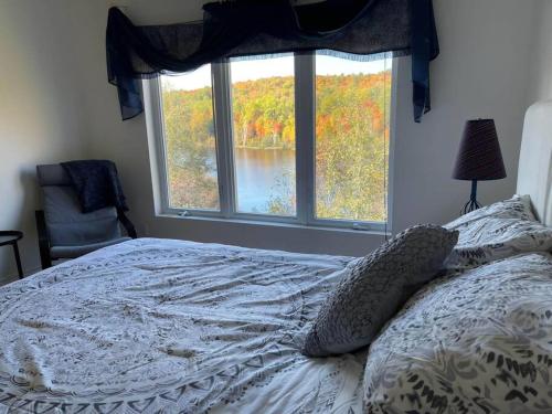 Ferme-NeuveにあるFull Chalet - 6 Bdrm Private / Beachfront / Kayaksの窓の前のベッド