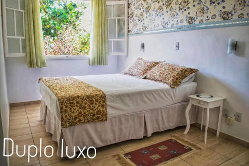 a small bedroom with a bed and a window at Pousada Della Vegas in Serra Negra