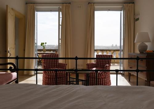 1 dormitorio con 2 sillas, mesa y ventanas en Penthouse w/ unique harbour view en La Valeta
