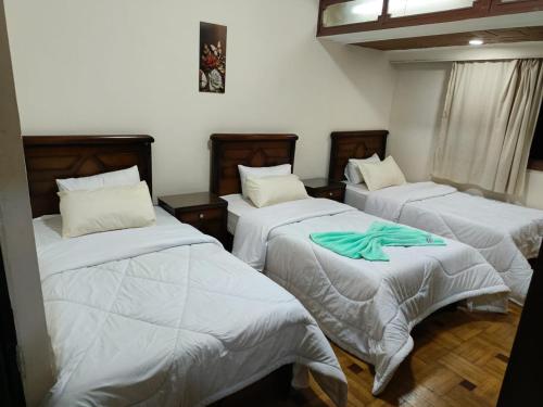 a room with three beds with white comforters at Hotel luna in Cairo
