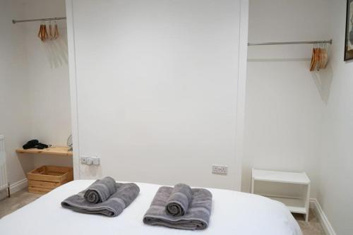 a white bed with three towels on top of it at Brixham Ground Floor Apartment in Torquay